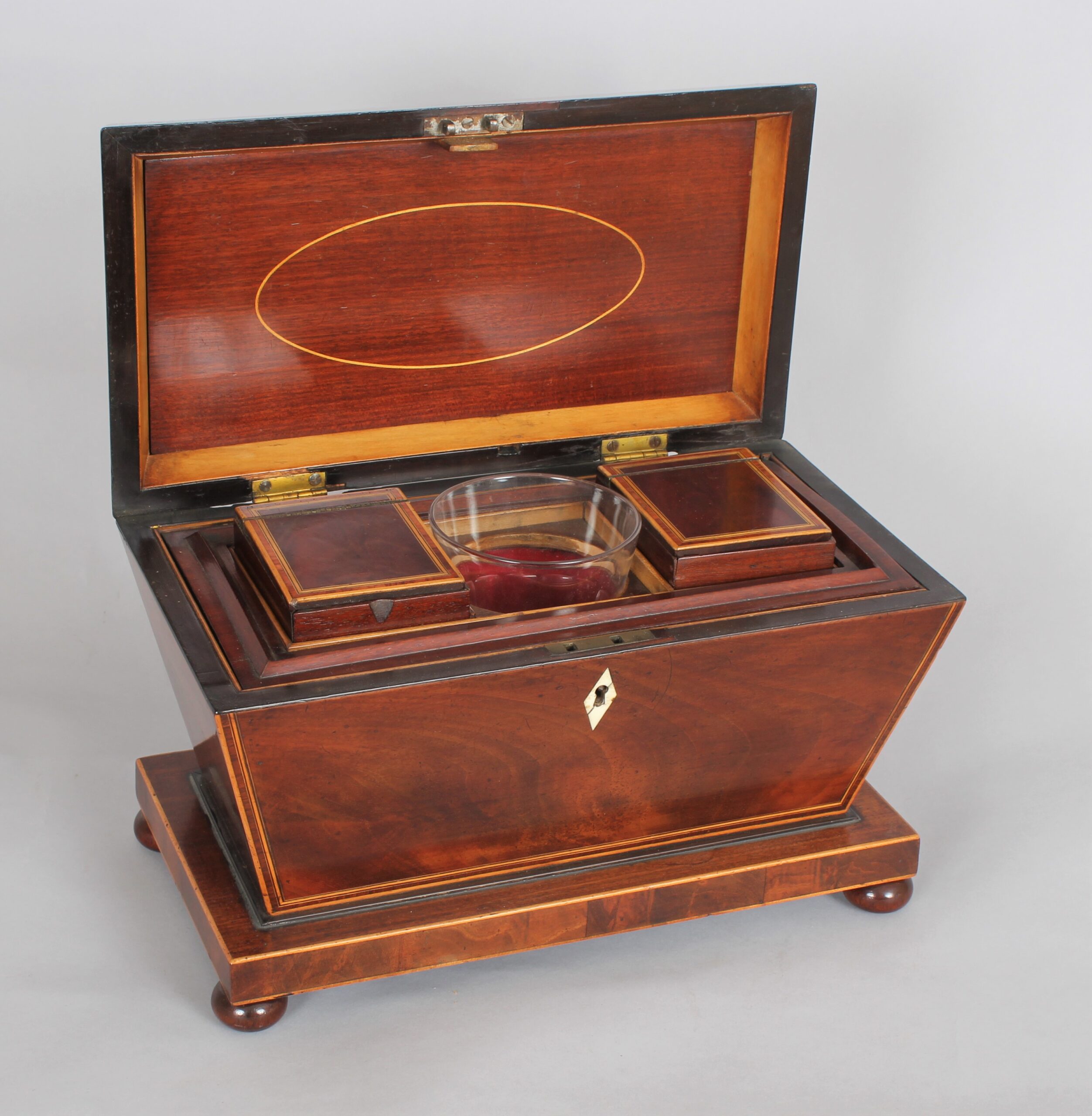 A bold mahogany sarcophagus shaped tea caddy